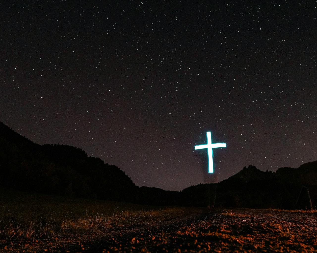 A scenic night view with a glowing cross under a starry sky, evoking spirituality.